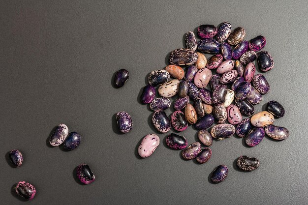 assorted multicolored beans scattered on black stone background. raw healthy ingredient for cooking useful food, top view