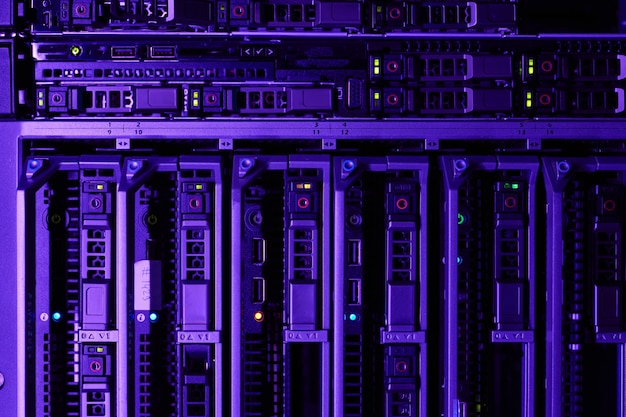 background image of rack servers in supercomputer network lit by blue and violet light, copy space