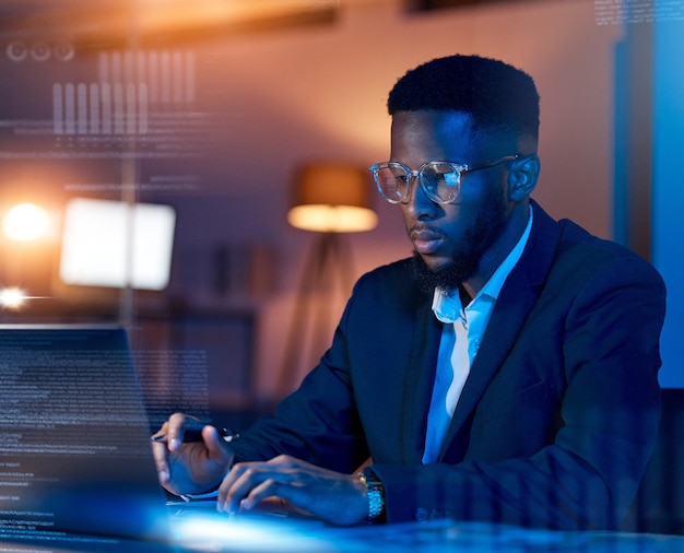 Black man in business code with laptop and hologram analytics and programmer in office at night dashboard and overlay Information technology data analysis and graph with software development