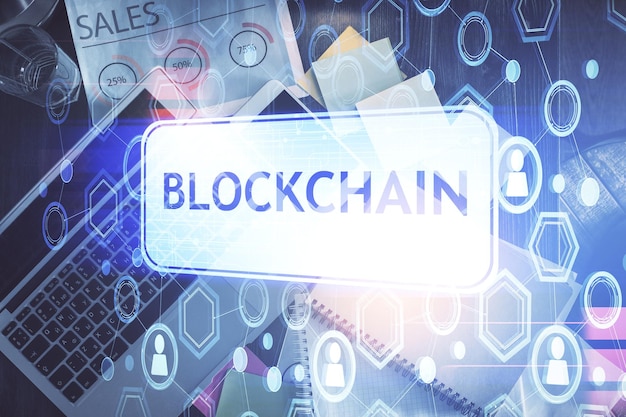 Blockchain-teemaiset hologrammi piirrokset tietokoneen yllä työpöydän taustalla. Yläkulma. Kaksi valotusta.