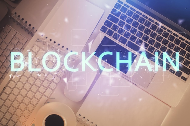 Blockchain-teemaiset hologrammi piirrokset tietokoneen yllä työpöydän taustalla. Yläkulma. Kaksi valotusta.