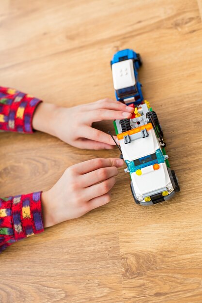 Boy's hands move toy truck. Child playing with toy vehicle. Technicians need to hurry. Power of imagination.