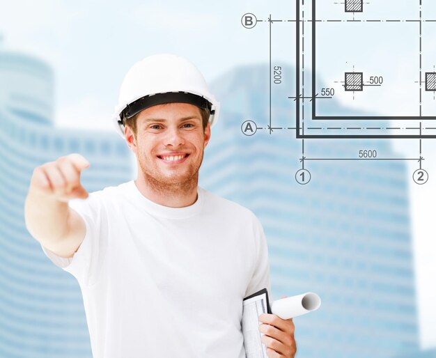 building, developing, consrtuction and architecture concept - male architect in white helmet pointing at you
