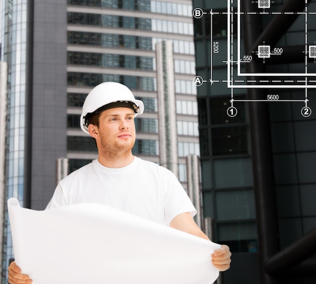 building, developing, construction and architecture concept - male architect in helmet looking at blueprint