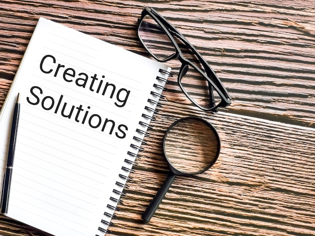 Business and idea concept. Notebook written creating solutions with pen, eye glasses and magnifier.