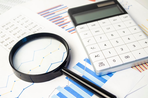 Business document magnifying glass and calculator on grey reflection