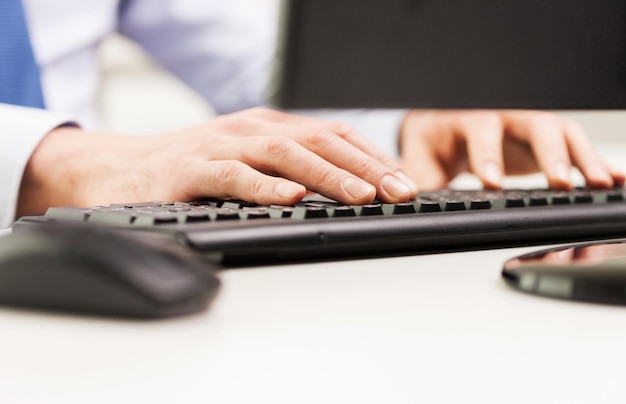 business, people and technology concept - close up of businessman hands typing on computer keyboard at office