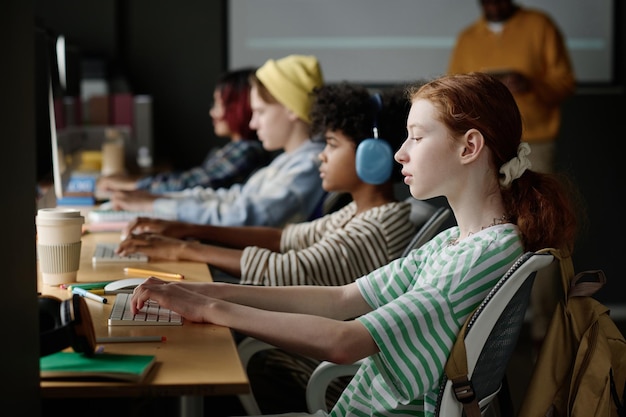 Caucasian girl typing on computer during coding class