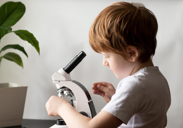 Child using microscope Schoolboy researching glasses with laboratory materials Science education