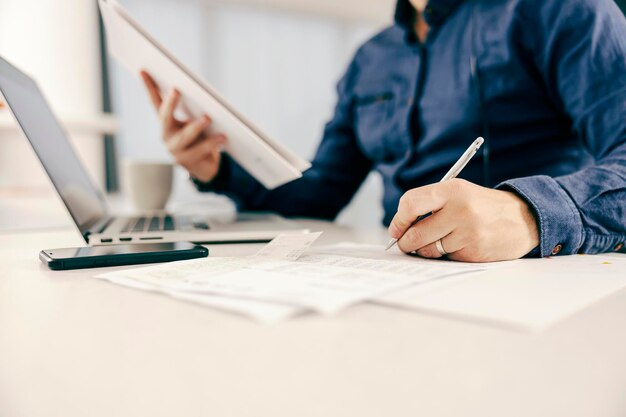 Close up of a entrepreneur writing down paperwork and working online from home