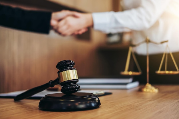 Close-up of gavel against businessmen handshaking in office