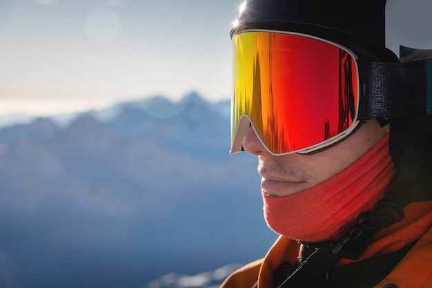 Close-up portrait of a guy holding skis in winter he is wearing sportswear such as a helmet and