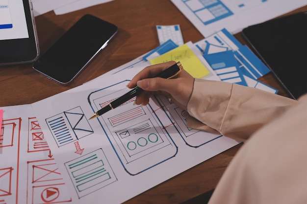 Close up ux developer and ui designer brainstorming about mobile app interface wireframe design on table with customer breif and color code at modern officeCreative digital development agency