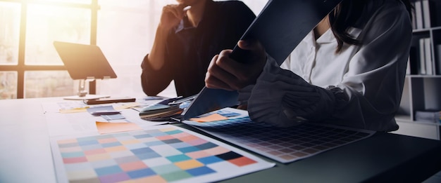 Close up ux developer and ui designer brainstorming about mobile app interface wireframe design on table with customer breif and color code at modern officeCreative digital development agency