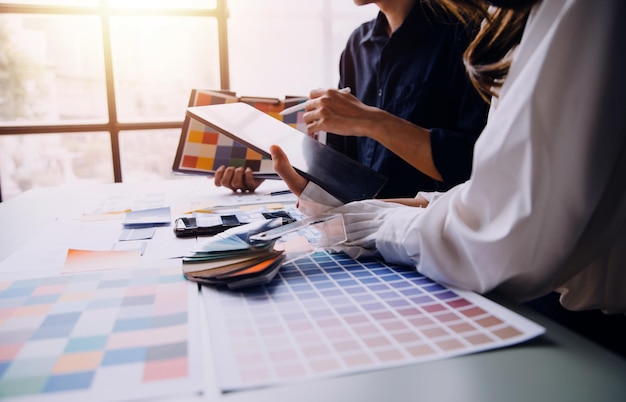 Close up ux developer and ui designer brainstorming about mobile app interface wireframe design on table with customer breif and color code at modern officeCreative digital development agency