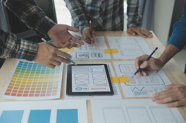 Close up ux developer and ui designer brainstorming about mobile app interface wireframe design on table with customer breif and color code at modern officeCreative digital development agency