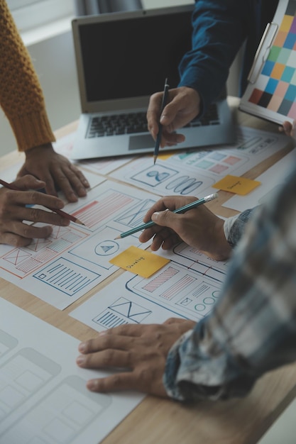 Close up ux developer and ui designer brainstorming about mobile app interface wireframe design on table with customer breif and color code at modern officeCreative digital development agency