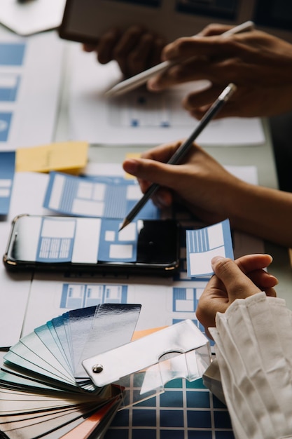 Close up ux developer and ui designer brainstorming about mobile app interface wireframe design on table with customer breif and color code at modern officeCreative digital development agency
