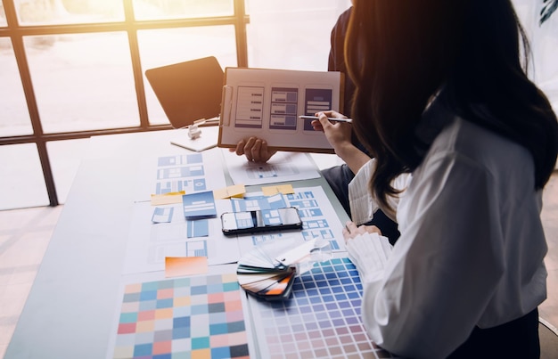 Close up ux developer and ui designer brainstorming about mobile app interface wireframe design on table with customer breif and color code at modern officeCreative digital development agency