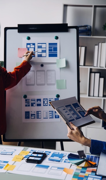 Close up ux developer and ui designer brainstorming about mobile app interface wireframe design on table with customer breif and color code at modern officeCreative digital development agency