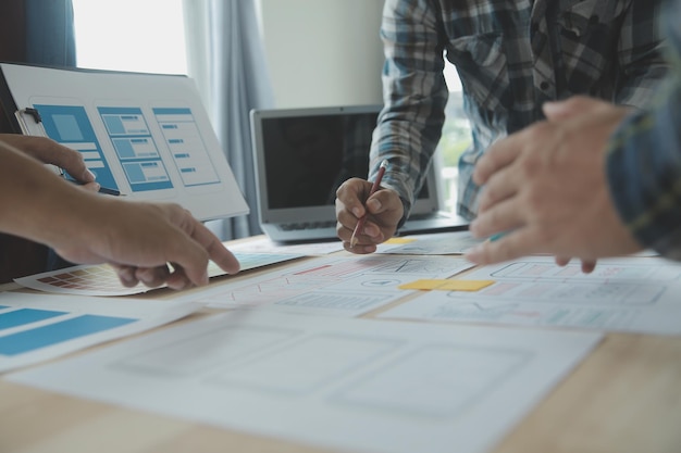 Close up ux developer and ui designer brainstorming about mobile app interface wireframe design on table with customer breif and color code at modern officeCreative digital development agency