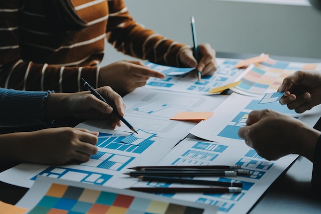 Close up ux developer and ui designer brainstorming about mobile app interface wireframe design on table with customer breif and color code at modern officeCreative digital development agency