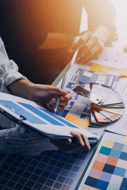 Close up ux developer and ui designer brainstorming about mobile app interface wireframe design on table with customer breif and color code at modern officeCreative digital development agency