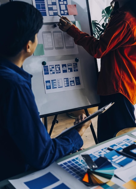 Close up ux developer and ui designer brainstorming about mobile app interface wireframe design on table with customer breif and color code at modern officeCreative digital development agency