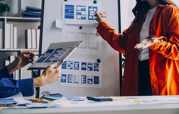 Close up ux developer and ui designer brainstorming about mobile app interface wireframe design on table with customer breif and color code at modern officeCreative digital development agency