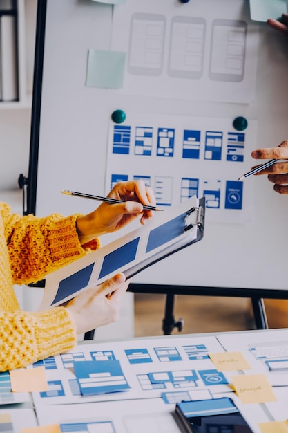 Close up ux developer and ui designer brainstorming about mobile app interface wireframe design on table with customer breif and color code at modern officeCreative digital development agency