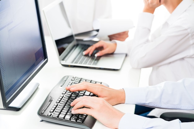 Closeup of a Businesspeople Working with Laptop and Computer