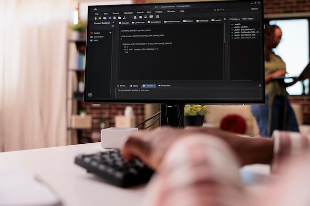 closeup of african american programmer writing code on personal computer typing keyboard while girlfriend is working remote on laptop. system developer at home developing software on pc.