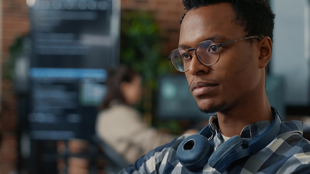 Closeup portrait of software engineer writing code fixing glasses and smiling sitting at desk. Database admin developing algorithms for artificial intelligence to innovate online cloud computing.