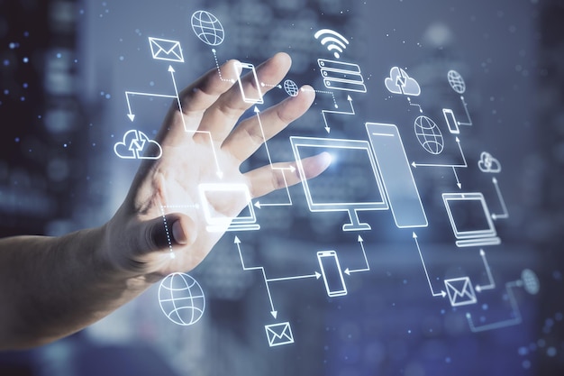 Cloud storage and computing technology concept with man hand on virtual touch screen with digital electronic devices connected between each other on blurred night city background