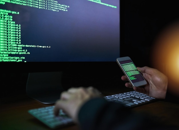 Code hands and technology with hacker typing on keyboard to break cyber security firewall at night Computer data theft and phone with person in office to bypass password or script protocol