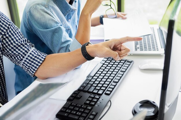 Colleagues discussing over computer at desk in office