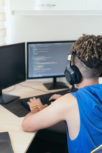 Computer programmer sitting at desk and typing on computer keyboard while creating code while working at home