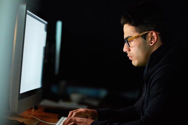 Computer typing and man at night for software development programming update and information technology Focus research and geek or programmer person on desktop screen for website cyber security