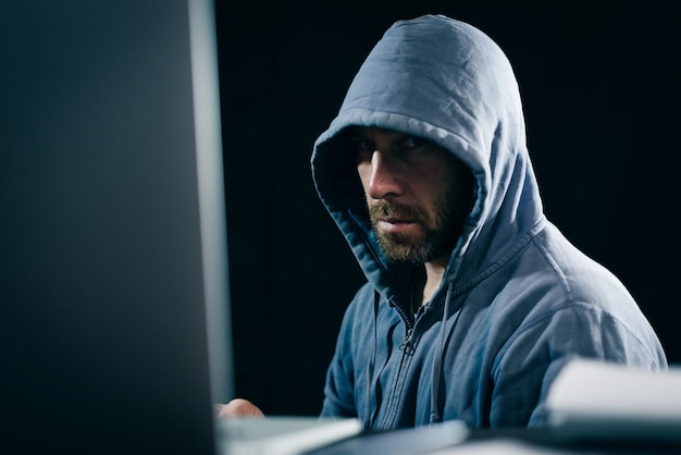 Criminal bearded man hides his face under the hood, does something illegal