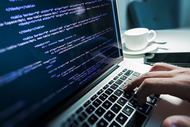 Cropped hand of programmer coding on laptop