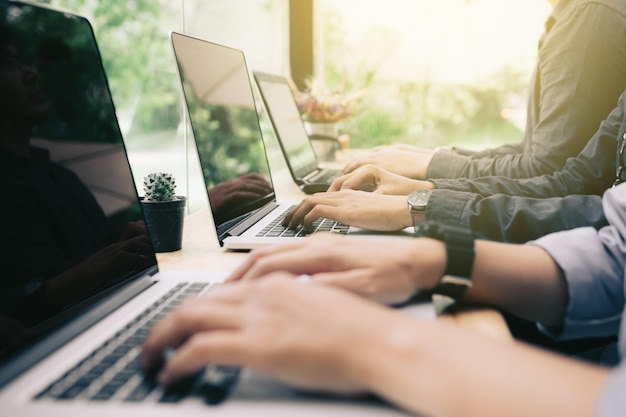 Cropped hands of businessmen using laptops at desk in office
