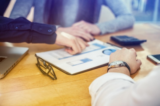 cropped image of business people discussing data at table in office