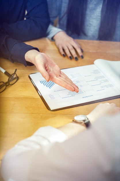 Cropped image of business people discussing data at table in office