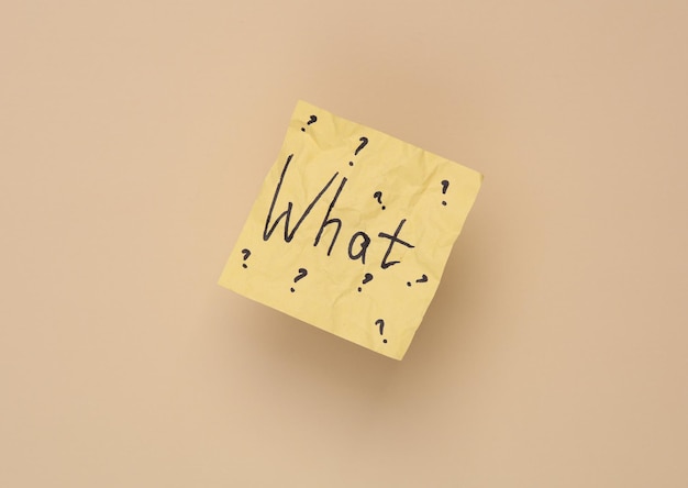crumpled memo paper with the question what on a beige background