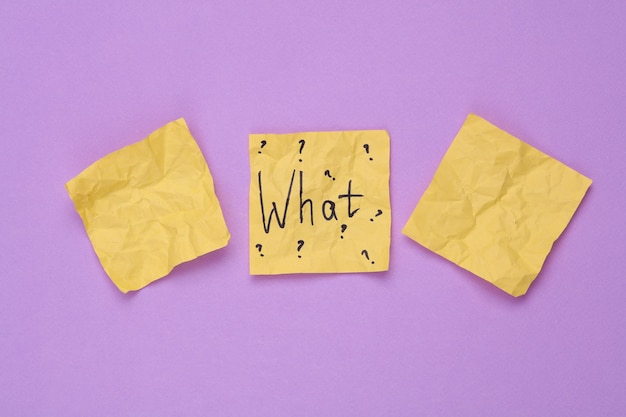 crumpled memo paper with the question what on a purple background