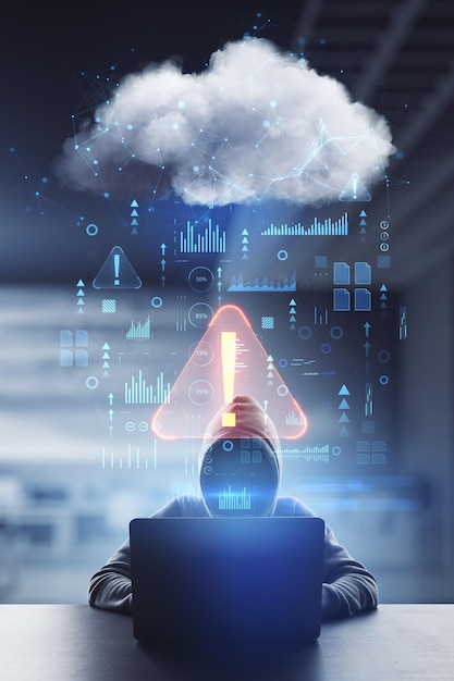 Cyber attack and hacking concept with front view on faceless hacker in hoody typing on laptop and abstract digital data cloud network interface with exclamation point double exposure
