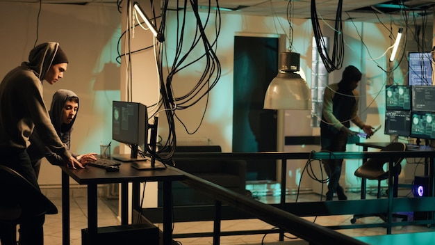 Cyber criminals working on breaking network system, using hacktivism concept to steal data. People committing cyberattack and identity theft, making privacy threats. Tripod shot.
