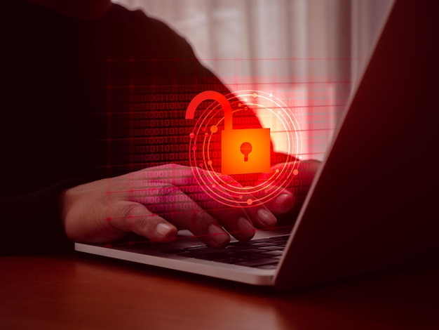 Cyberattack and internet crime scam hacking and malware concepts Unlocked padlock icon on red digital binary code data numbers on dark virtual screen while hackers hands typing on laptop computer