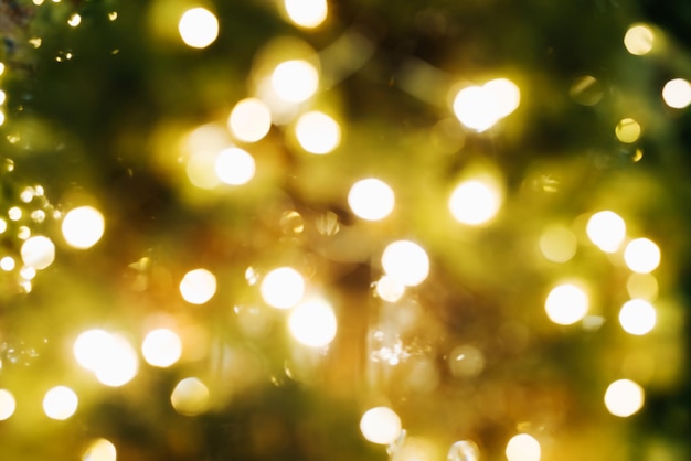 Defocus Christmas tree decorated with glowing garland, close-up. Abstract xmas festive background. Blurred Christmas New Year lights