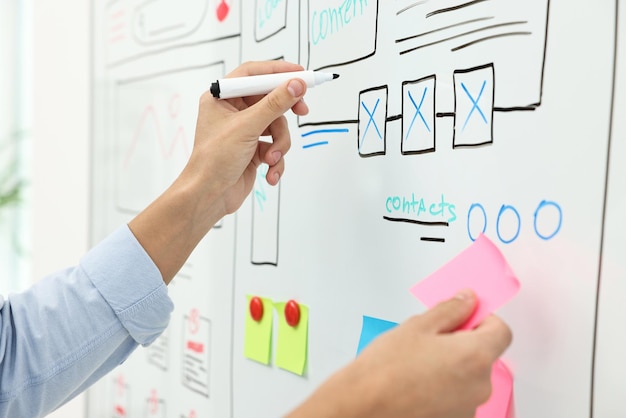 Developing UI design Man drawing website wireframe on whiteboard indoors closeup